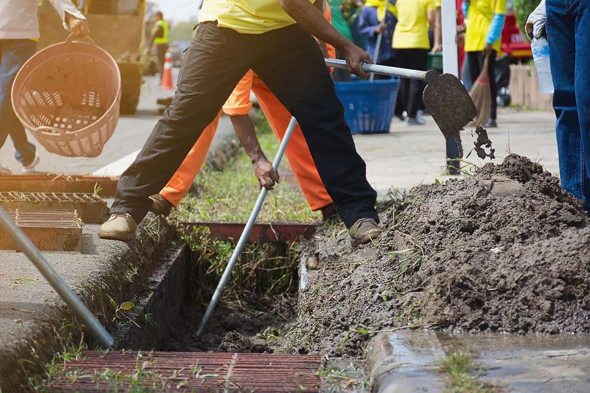 Workers clearing debris from a drain