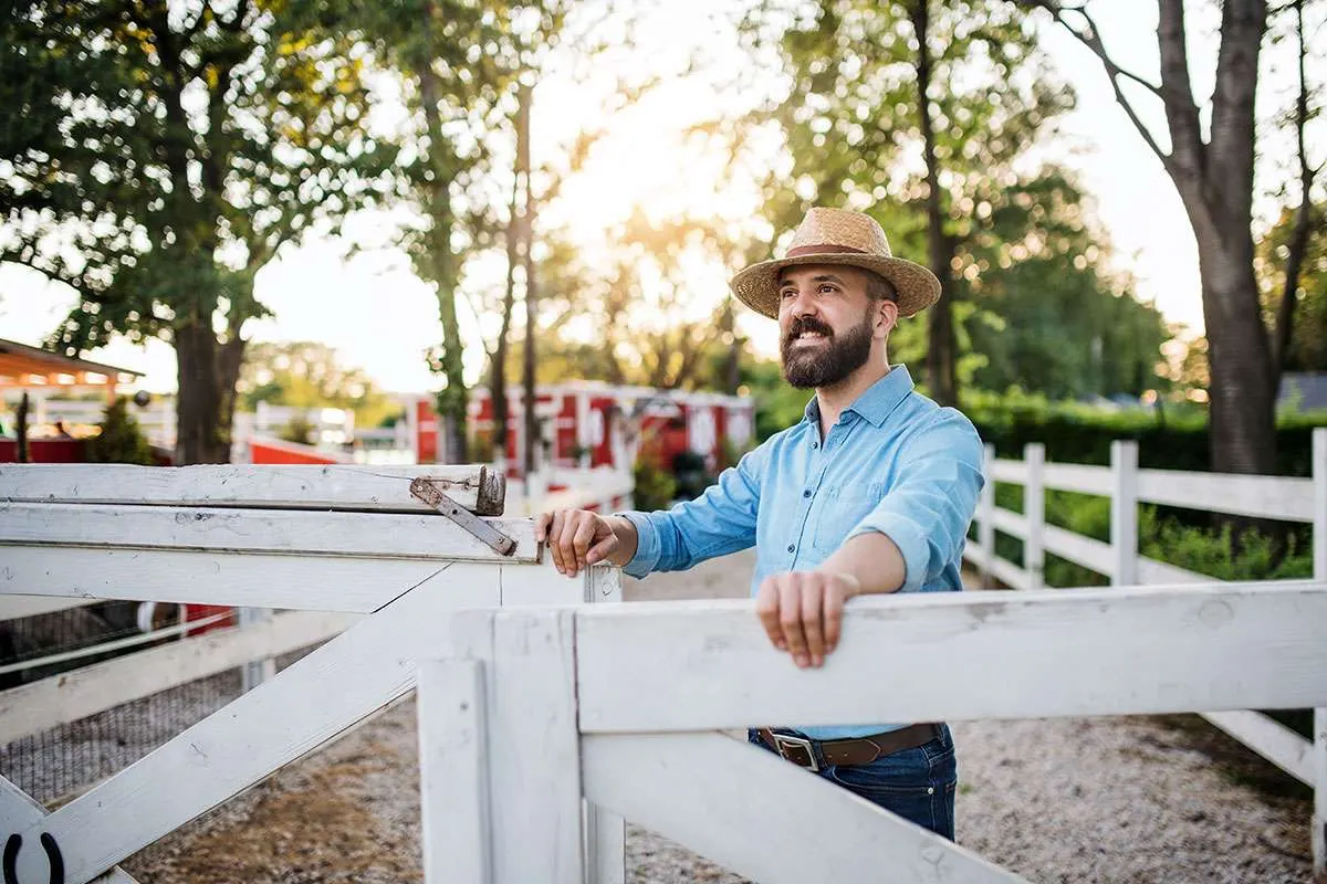 A farmer unlocking a wooden gate