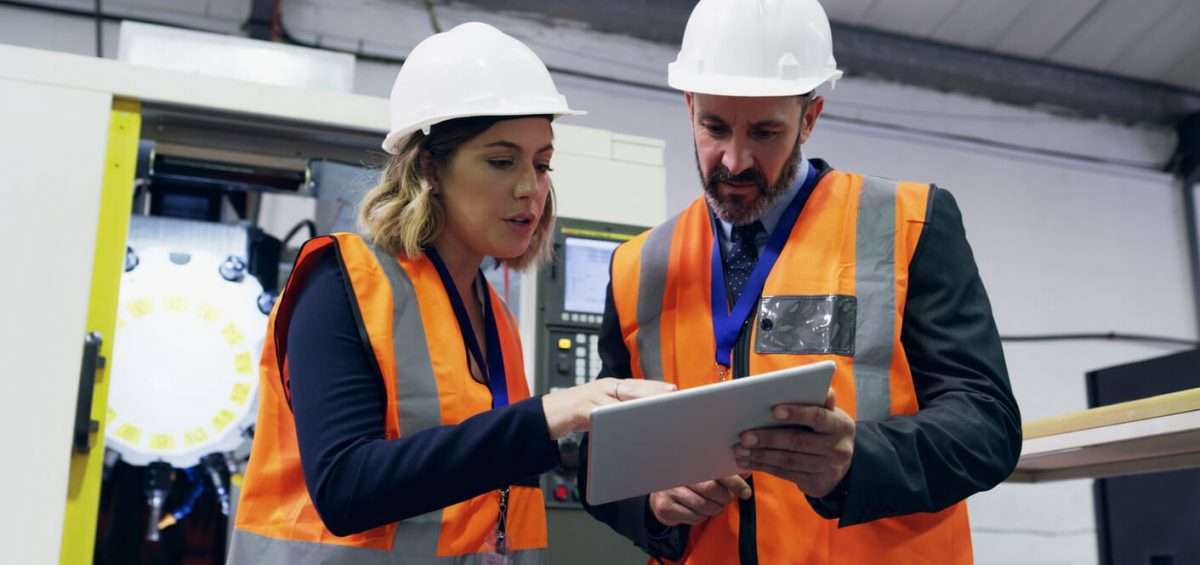 man and woman looking at tablet assessing equipment report and analytics