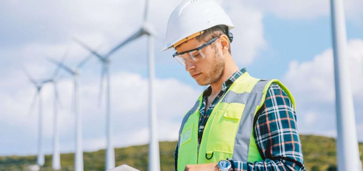 man looking at tablet servicing wind farm