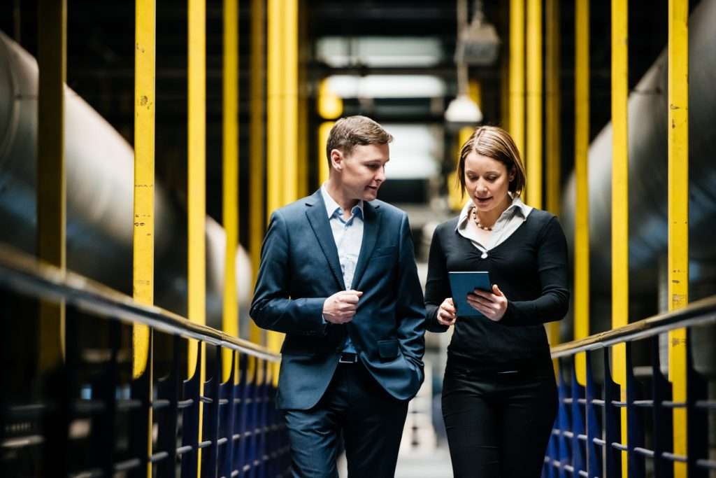 Two business owners walking in a hallway while discussing data security certifications - ISO 27001 and GDPR certifications.