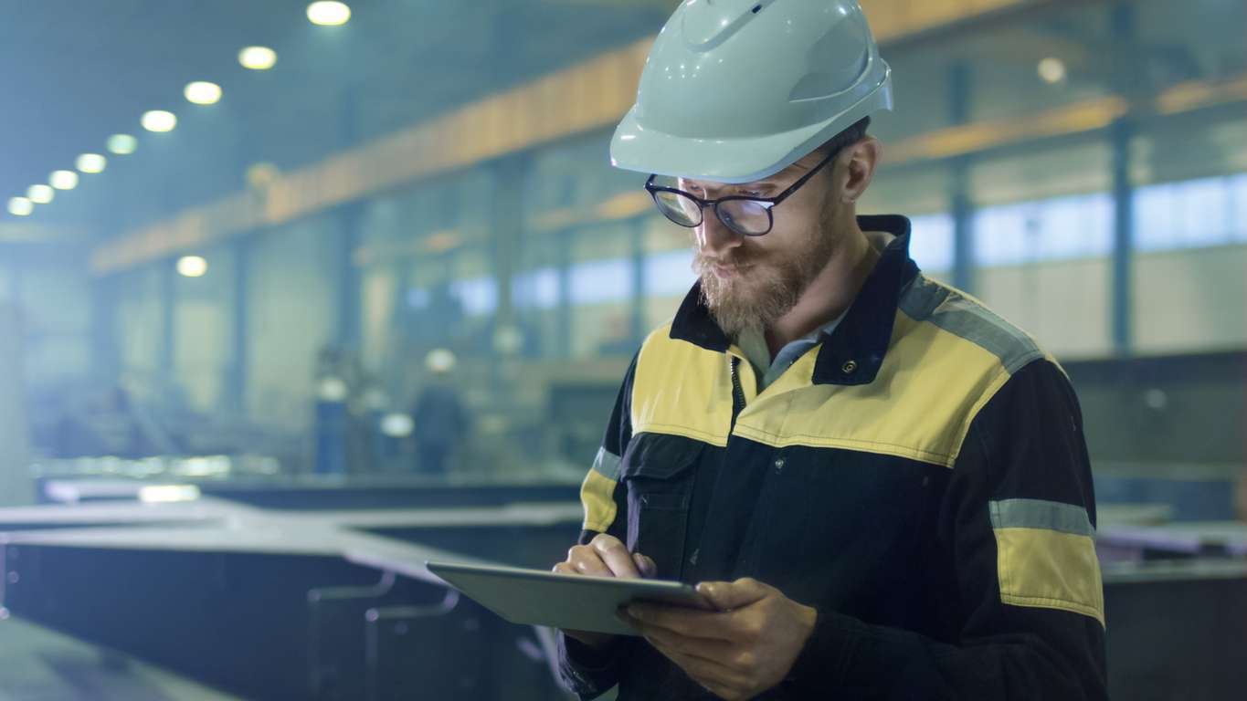 Male engineer using a tablet computer in a factory - using prescriptive maintenance to check machineries.