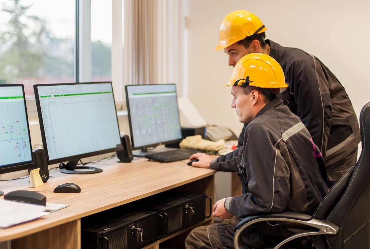 Two field service workers using a computer to access their field service management software.