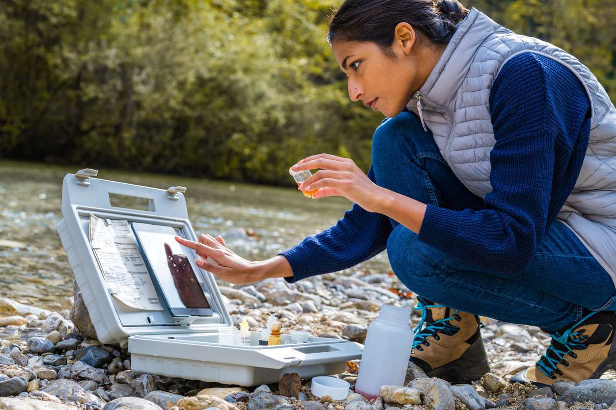 Woman getting water samples from a lake - environmental inspections.