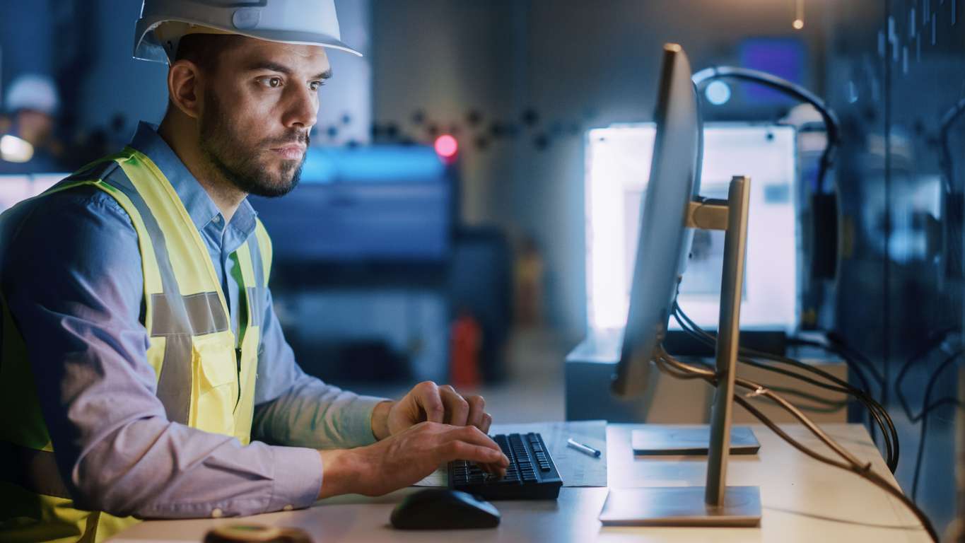 Male engineer in an office using a computer while updating important data.